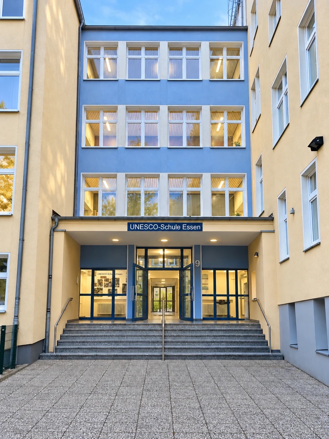 Haupteingang der UNESCO-Schule Essen mit geöffneten Glastüren und Treppe